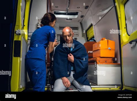 Nurse In Blue Medical Uniform Puts Oxygen Mask On Man Sitting In