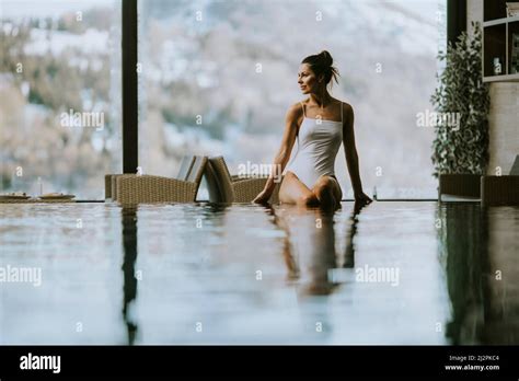 Im Winter Sitzt Eine Attraktive Junge Frau Im Bikini Am Pool Im Hallenbad Stockfotografie Alamy