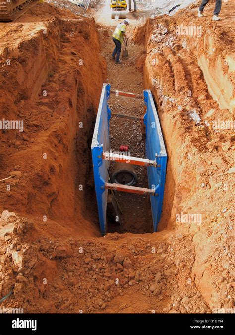 Men Working In Deep Trench Excavation Under Protection Of Hydraulic