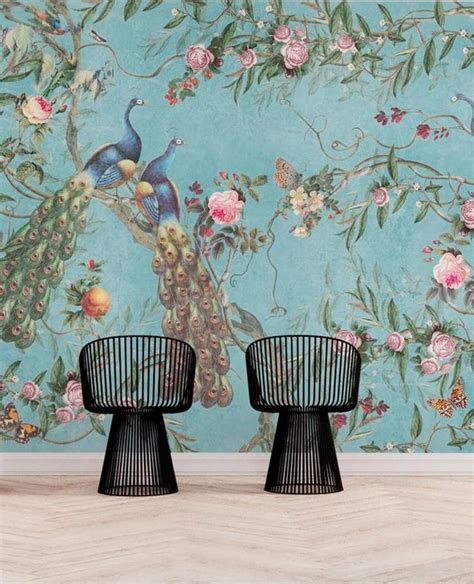 two chairs in front of a wall with flowers and peacocks on it, against ...