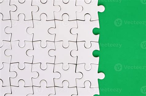 Fragment Of A Folded White Jigsaw Puzzle On The Background Of A Green