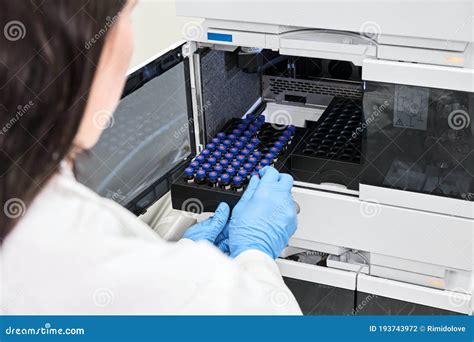 Scientist In A White Lab Coat Putting Vial With A Sample Into