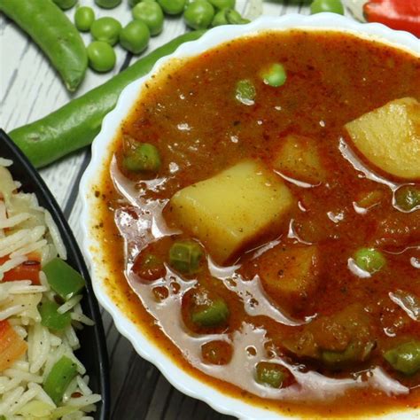 There Is A Bowl Of Stew With Rice And Peas On The Table Next To It