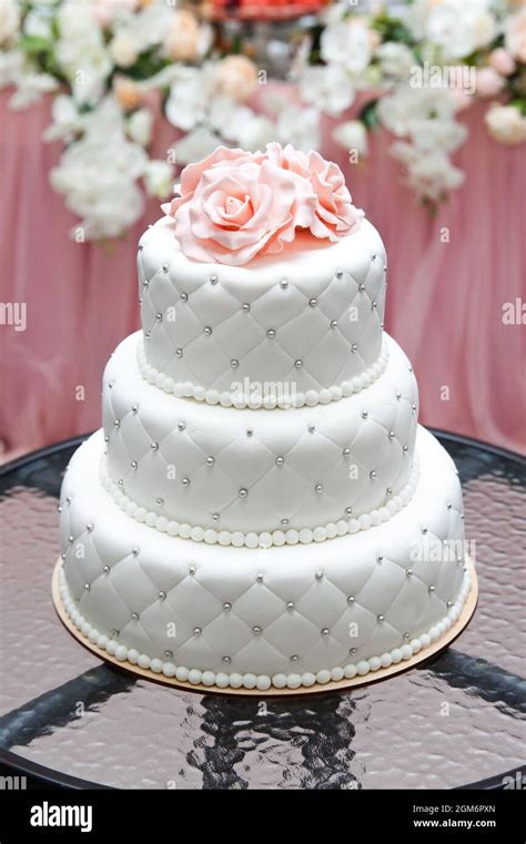 a multi level white wedding cake and pink flowers on top. Big cake. Birthday cake Stock Photo ...