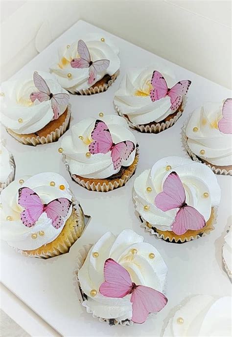 There Are Many Cupcakes With White Frosting And Pink Butterfly