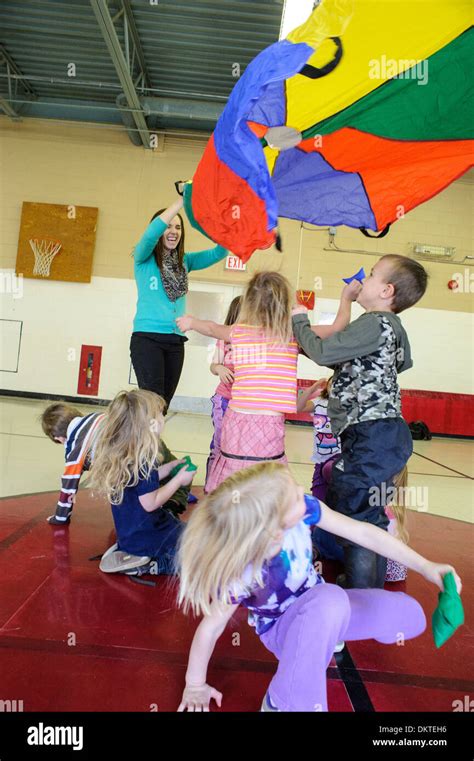 Pre School Children Playing With Rainbow Parachute In Gym Stock Photo