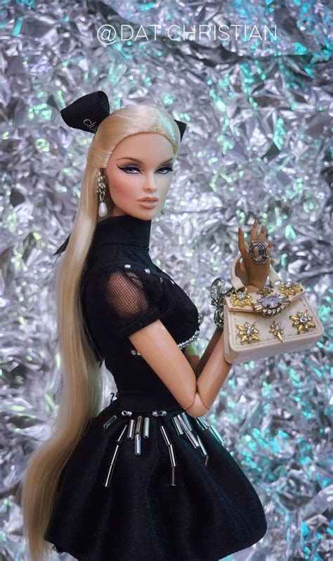 A Barbie Doll Holding A Purse And Wearing A Black Dress With Gold