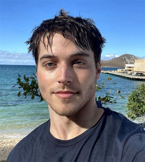 a man standing in front of the ocean taking a selfie