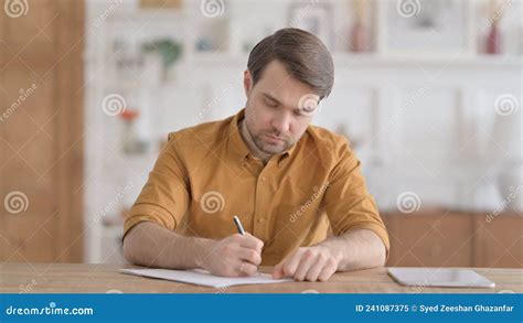 Young Man Thinking While Writing On Paper In Office Stock Image Image