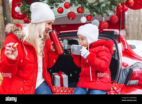 Bonne famille de maman blonde et petite fille assis dans la voiture décorée de noël dans la