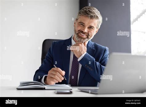 Successful Mature Businessman Wearing Suit Sitting At Desk With Laptop In Office Stock Photo Alamy