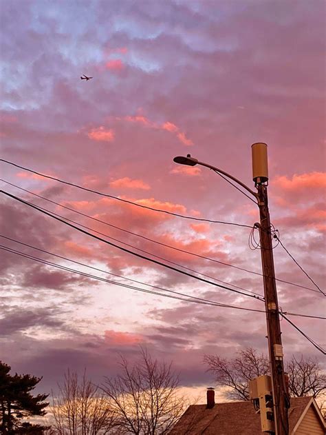 The Sky Is Pink And Purple As It Sets Behind Some Power Lines With A