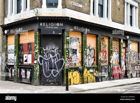 Religion Shop With Boarded Up Windows And Shutters Covered In Graffiti