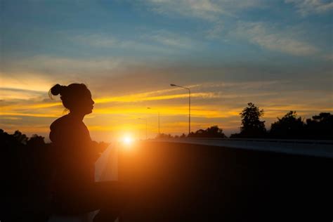 Mujer De Silueta En La Carretera Viendo La Puesta De Sol Amarillo Y