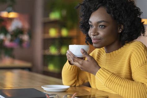 Dreamy African Young Woman Relaxing At Cafe Drinking Coffee Stock