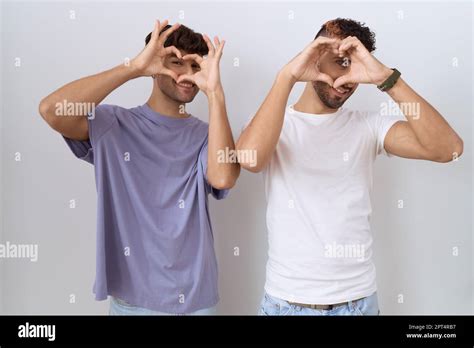 Homosexual Gay Couple Standing Over White Background Doing Heart Shape With Hand And Fingers
