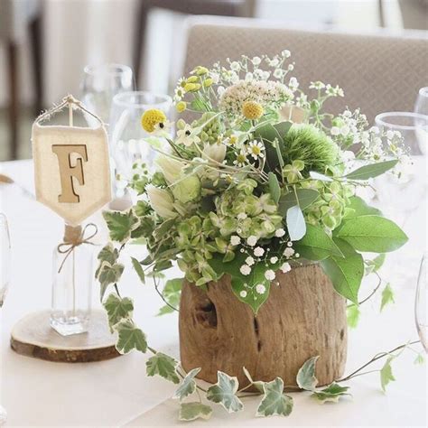 A Wooden Vase With Flowers And Greenery On Top Of A Table At A Wedding