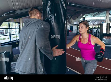 Male trainer giving boxing training to female athletic in fitness ...