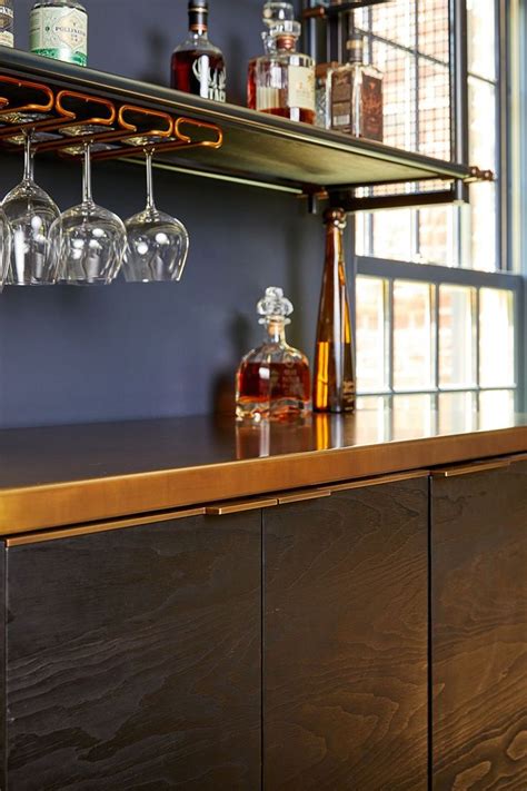 A Bar With Wine Glasses And Liquor Bottles On The Top Next To A Window