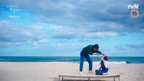 A Man And Woman Standing On Top Of A Surfboard Near The Ocean With