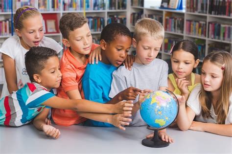 Niños de la escuela mirando el globo en la biblioteca Foto Premium