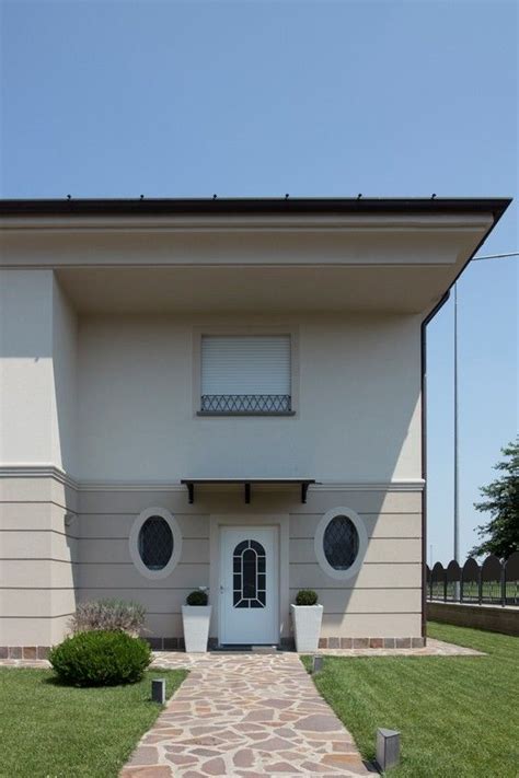 A White House With Two Round Windows And A Stone Path Leading To The