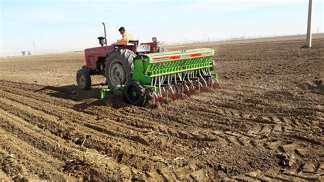 A Tractor Is Plowing The Field With Two People On Its Front End