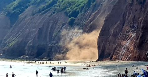Cliff collapse like thunder as stunned Devon beachgoers look on below