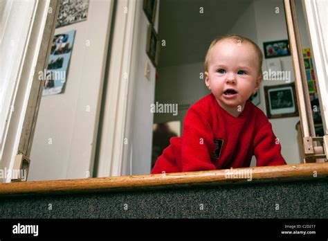 A Baby Boy Holding On To The Baby Safety Gate And Then Crawling Down