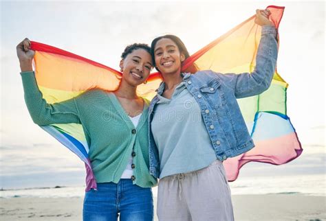 Woman Lesbian Couple And Pride Flag On Beach Together In Happiness For LGBTQ Community Or