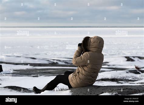 Mujer sentada en rocas de hielo en el borde de la bahía de Hudson en