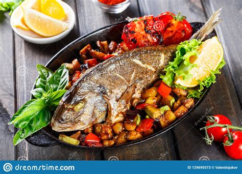 Baked Dorado Fish With Vegetables And Lemon On Pan On Wooden Background