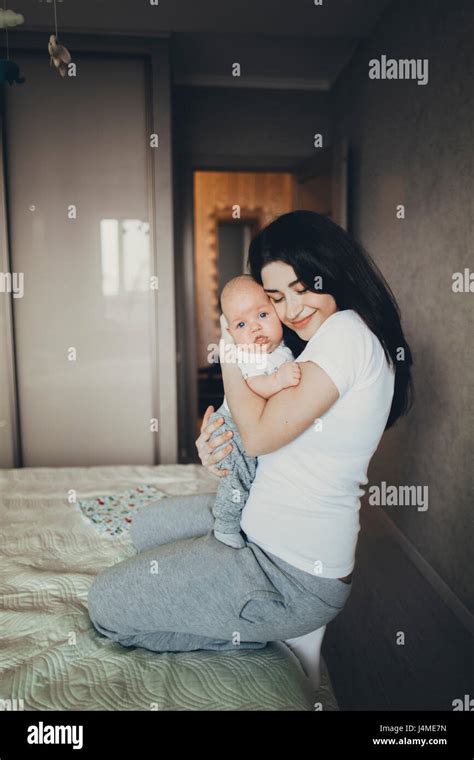 Caucasian Mother Kneeling On Bed Hugging Baby Son Stock Photo Alamy