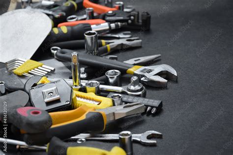 Handyman tool kit on black wooden table. Many wrenches and screwdrivers ...