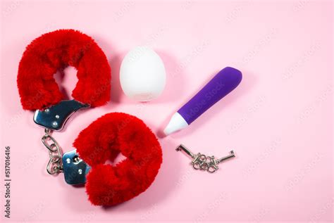 Red Sexy Fluffy Handcuffs With Keys And Vibrator On A Pink Background