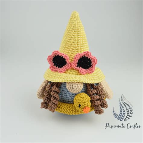 A Crocheted Doll Wearing A Hat And Holding A Duck