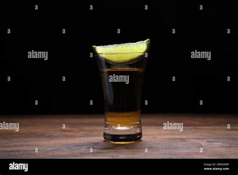 Mexican Tequila Shot With Lime Slice On Wooden Table Against Black