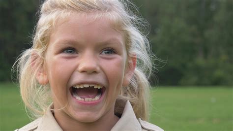 Small preschooler caucasian girl with blonde hair in jacket is smiling ...