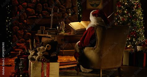 Santa Claus works at his desk, surrounded by Christmas decorations Stock Photo | Adobe Stock