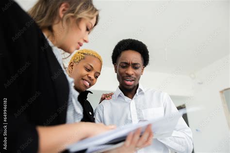 Blonde Real Estate Agent Leads The Way With A Warm Smile As The African Couple Follow Her