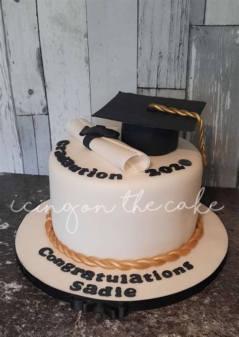 A Graduation Cake With A Mortar And Tassel On Top Decorated In White