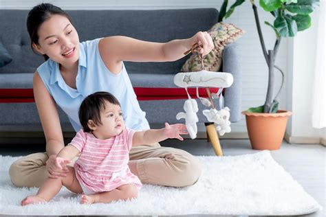 아시아 엄마와 딸은 7개월 된 딸이 바닥에 앉아서 장난감을 가지고 놀고 있다 프리미엄 사진