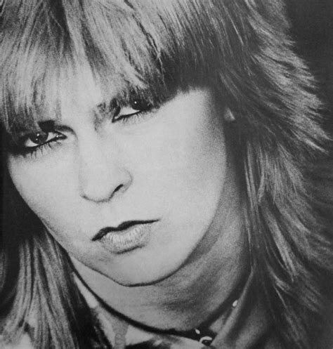 a black and white photo of a woman with long hair wearing a neck tie looking at the camera