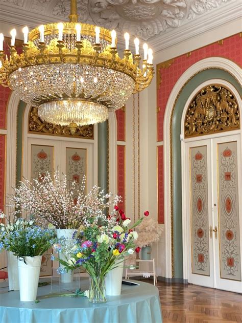 A Table With Flowers And Vases On It In A Room That Looks Like A Palace