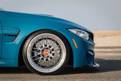 The Front End Of A Blue Sports Car With Chrome Rims And Wheels On It