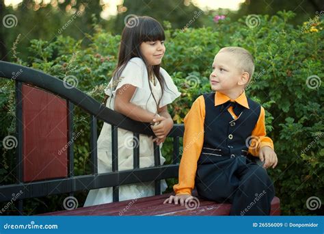 Rapaz Pequeno E Menina Que Sentam Se No Banco Imagem De Stock Imagem