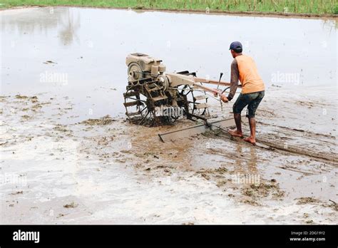 Indonesia Farmer Plowing A Rice Field Using Tiller Tractor Stock Photo