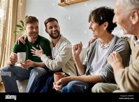 A Gay Couple Sits On A Couch With Parents All Smiling And Laughing Together Stock Photo Alamy