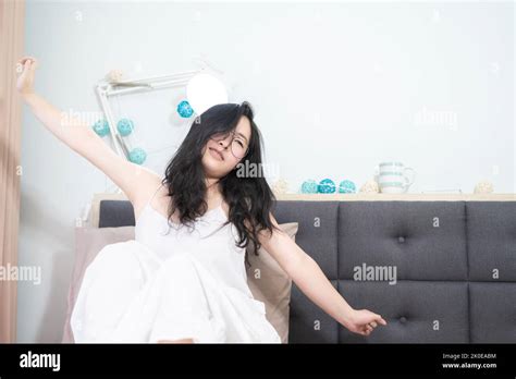 Asian Young Glasses Woman Stretches Oneself On Her Bed In The Morning