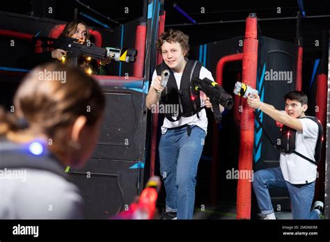 Laughing Players Mens And Womens Playing In Teams In Dark Laser Tag